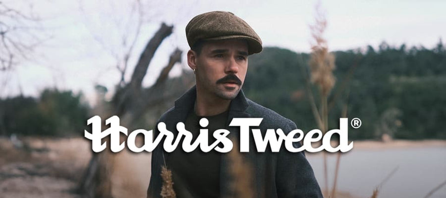 A man wearing a Harris Tweed newsboy cap by a river